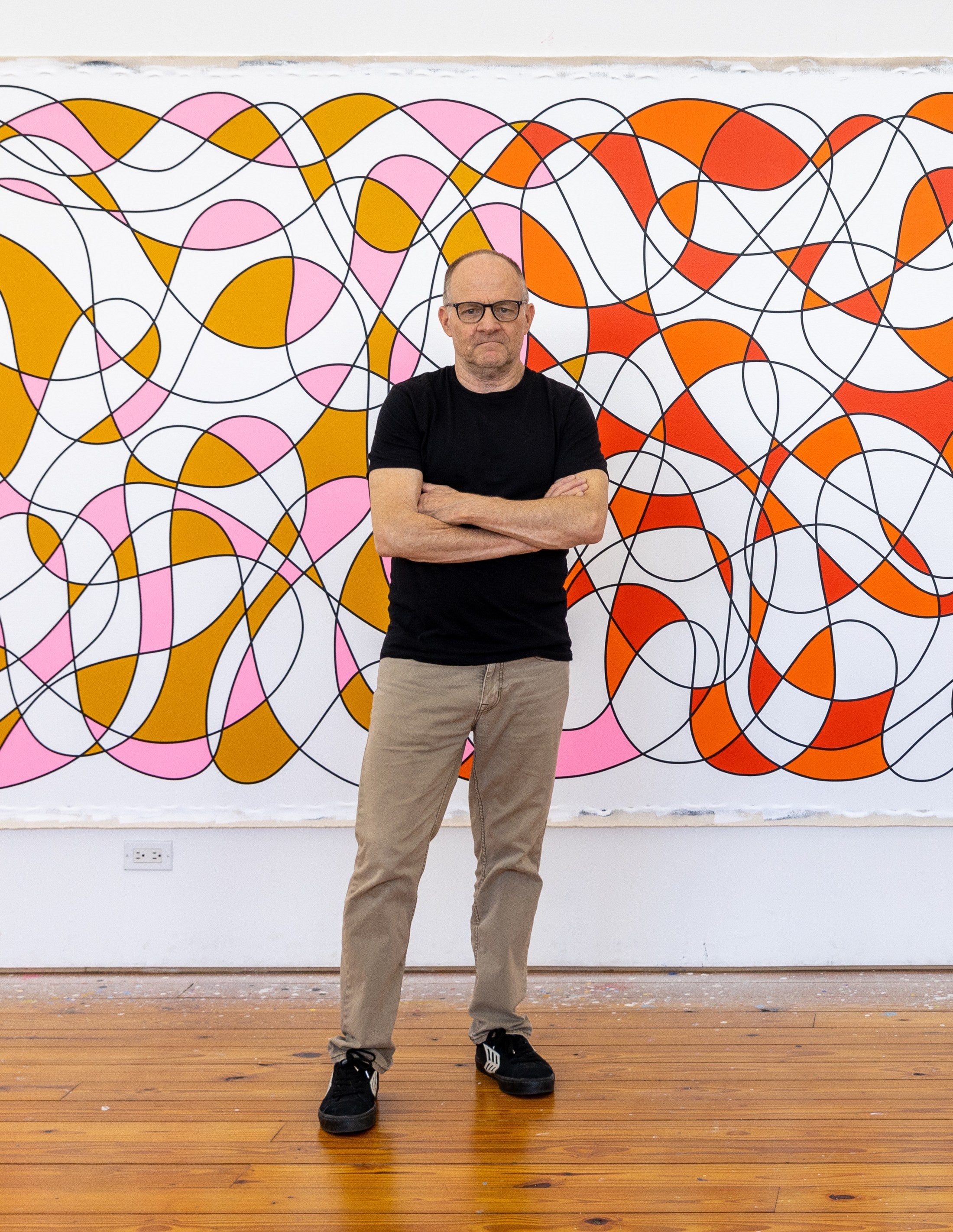 Aaron Parazette standing in front of one of his paintings